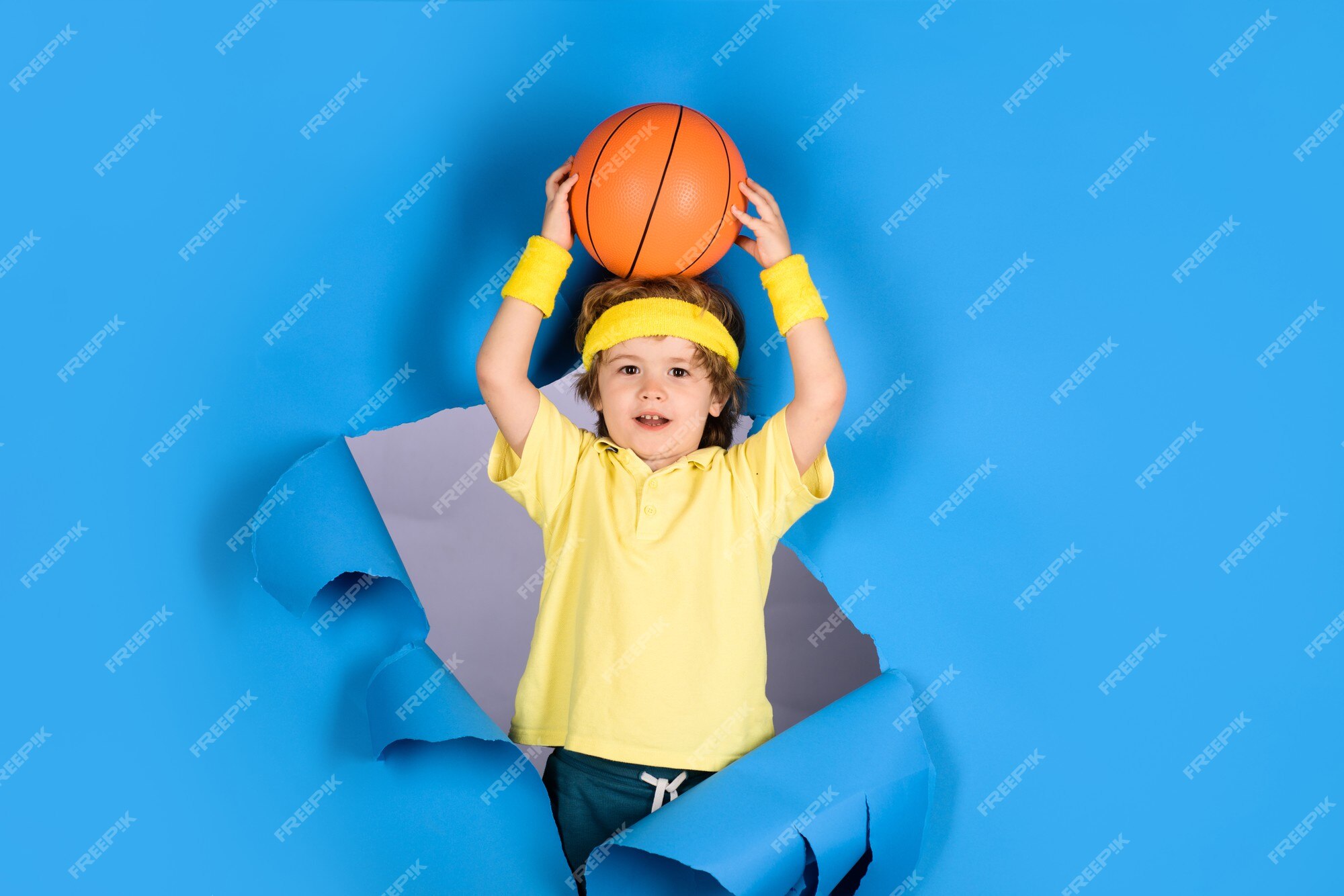 Gioco di allenamento di basket. Bambino sorridente con palla da basket che  mostra il pollice in