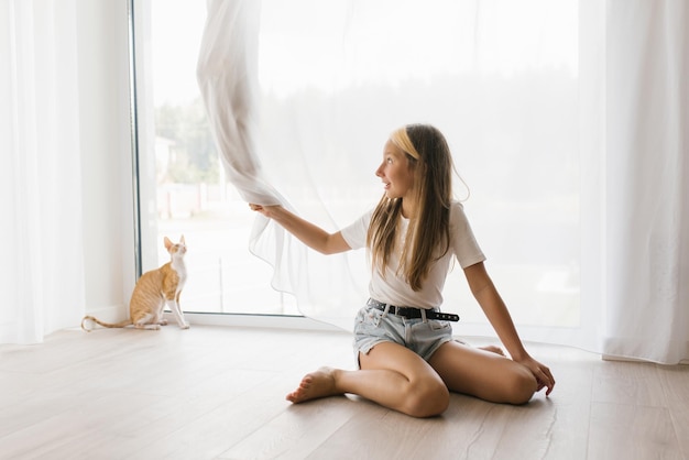 Little beautiful Caucasian mistress of a cornish rex cat a girl with a happy face in her free time