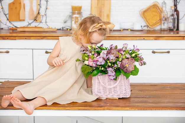 自宅のキッチンで花を持つ小さな美しい子供の女の子