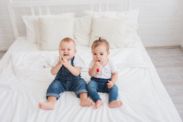 маленькие красивые дети мальчик и девочка сидят на кровати с зубными щетками