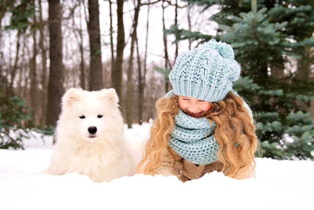 小さな美しい女の子、冬に彼女の犬と楽しんで雪の中でかわいい幸せなポジティブな子の子供