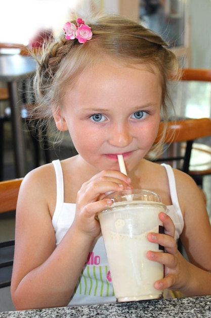 Little beautiful girl drinking tasty cocktail in fastfood