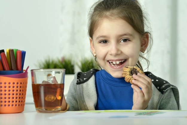 Little beautiful girl  drinking tea and eating cookie