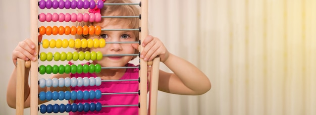 Little beautiful girl holding multi-colored abacus in her hands. Preschool girl with bright educational toys. education