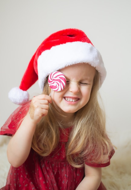 Little Beautiful Girl in Santa Hat rode feestjurk wachten op Kerstmis