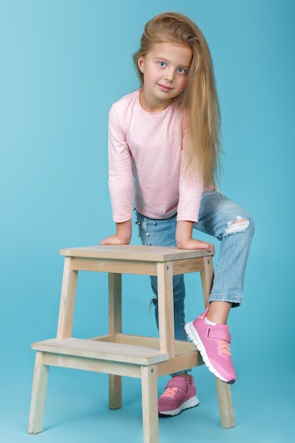 Little beautiful girl in pink sweater and jeans posing in studio