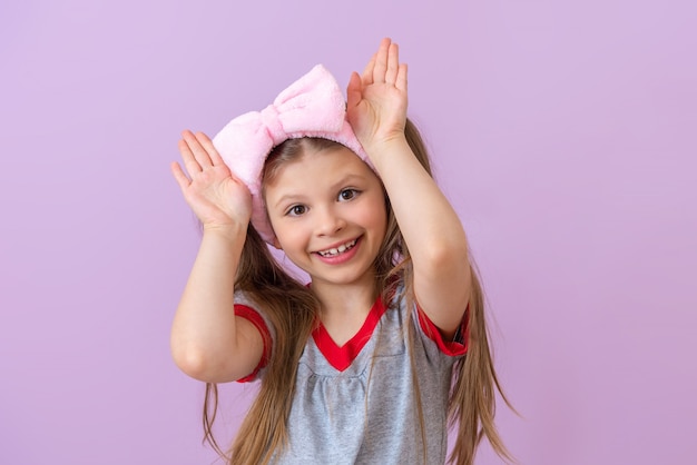A little beautiful girl shows the ears of a rabbit with her hands.