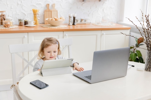 Little beautiful girl study at home while quarantine Cute child doing homework online sitting