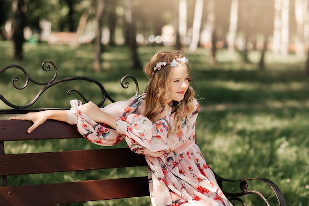 A little beautiful girl walks in a city park and dreams