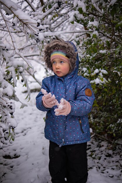 雪に覆われた森の真ん中に一人で立っている冬服を着た美しい少女