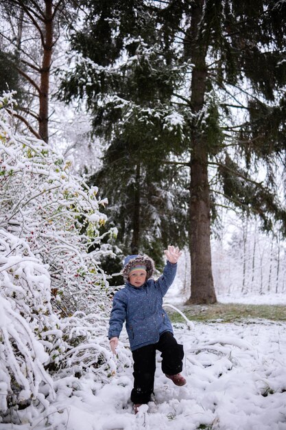 Little beautiful girl in winter clothes standing alone in the middle of a snowy forest