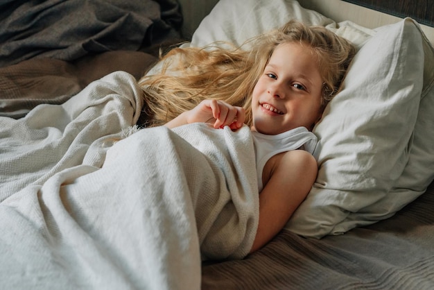 Little beautiful longhaired girl preschooler wakes up in the
morning sleeps with a smile on her face