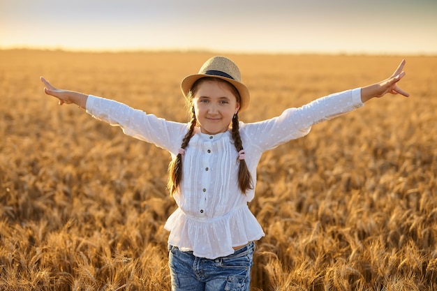 Маленькая красивая улыбающаяся девочка на золотом пшеничном поле