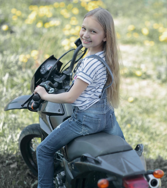 自由の冒険と旅行の象徴として彼女のバイクに乗る小さなバイカーの女の子