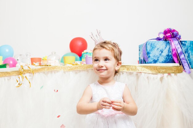 Piccola ragazza di compleanno con corona sulla testa che tiene palloncini colorati. la ragazza principessa alla festa di compleanno