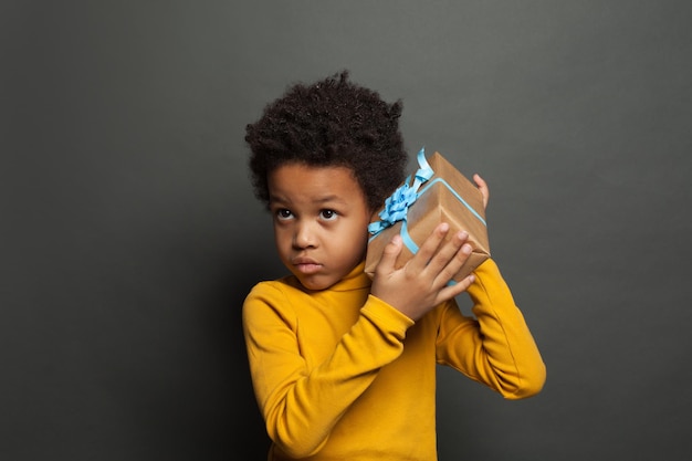 Little black child boy holding gift on black background