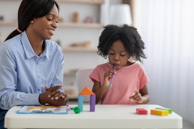 Little black girl playing with ball and straw at kindergarten