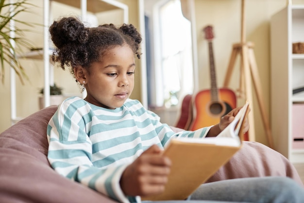 Little black girl reading book at home