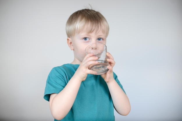 小さな金髪の少年は水を飲みます