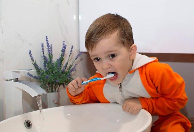 家庭風呂で歯磨きを学ぶ金髪の少年。健康を維持する方法を学ぶ子供。ヘルスケアの概念。