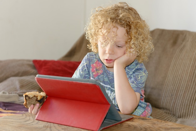 Little blond boy using tablet computer