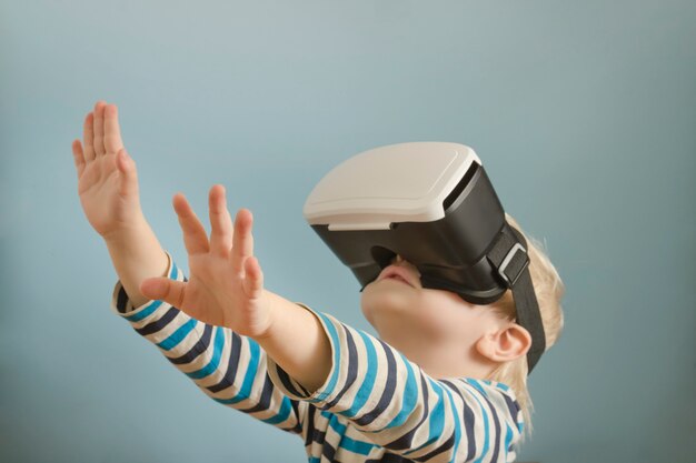 Маленький белокурый мальчик с очки виртуальной реальности.