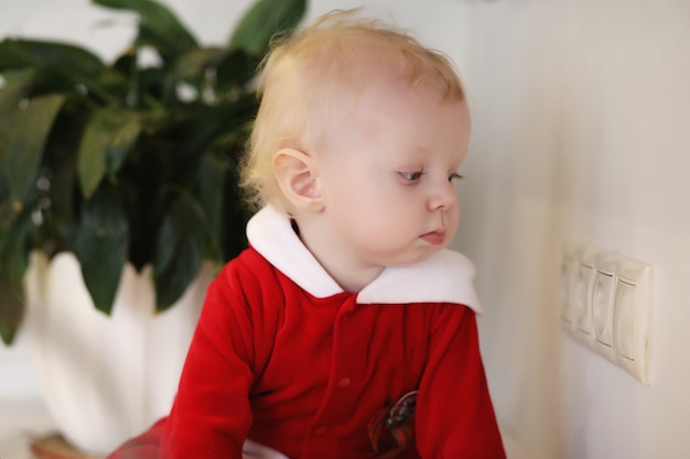 Little blond child in the kitchen sits on a table