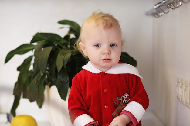 Little blond child in the kitchen sits on a table