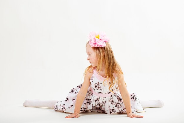 Little blond girl in a dress sitting on the floor