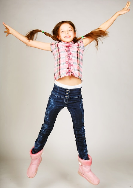 Little blond girl jumps on a gray background