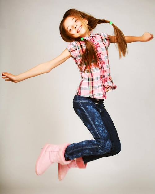 Little blond girl jumps on a gray background