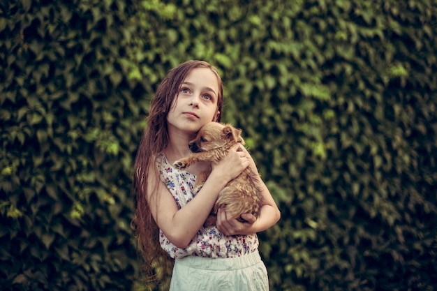 公園でペットの犬の屋外にいる小さなブロンドの女の子。女の子は小さな子犬が大好きです。