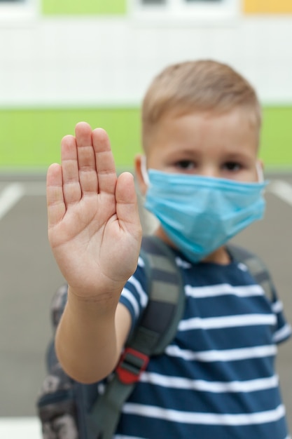 Маленький белокурый школьник в маске во время вспышки вируса короны