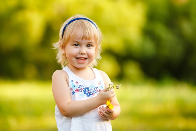 작은 금발 2-3 세 소녀 여름 공원에서 재생 및 꽃 냄새. 어린이 활동 개념
