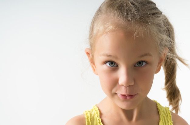 Little blonde girl of 5 years old looks inquiringly in surprise at the frame closeup isolated on a light background
