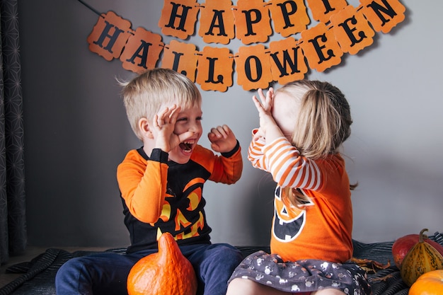 A little blonde girl and a boy in a pumpkin costume for Halloween, trick or treat, children celebrate Halloween. Ready for the trick or treat holiday