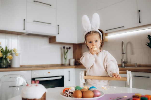 Little blonde girl coloring eggs for Easter holiday at home