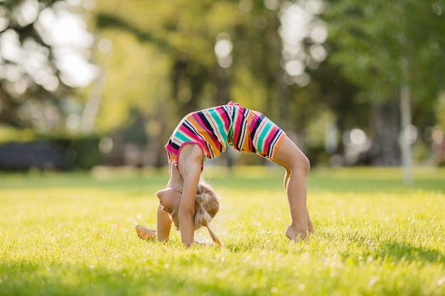 写真 夏に緑の芝生で体操をしている金髪少女