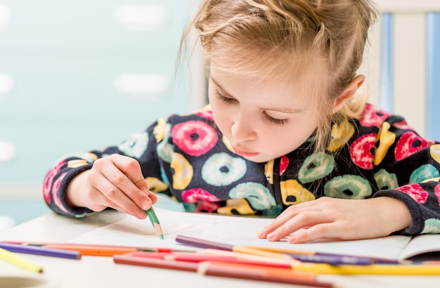 Little blonde girl draws with pencils