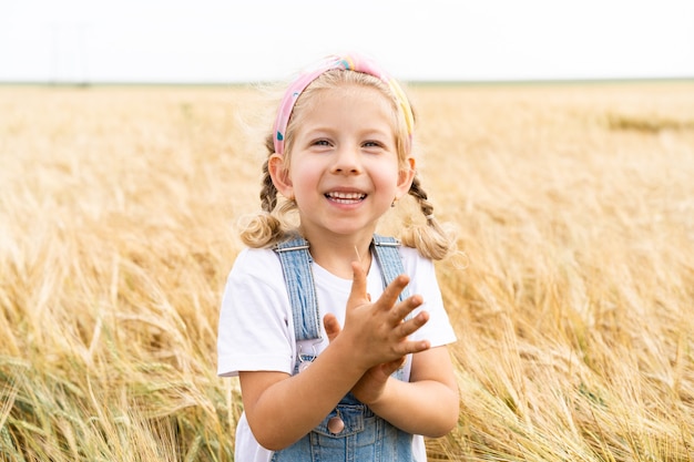 Little blonde girl in the field of rye, grain harvest.