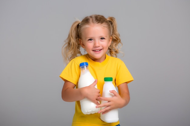 little blonde girl holding plastic bottles of milk