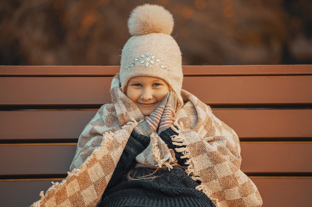 写真 ベンチの公園で格子縞の小さなブロンドの女の子