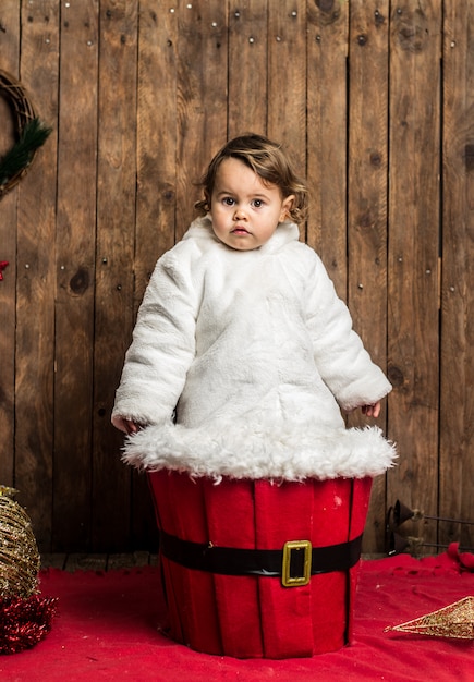 Little blonde girl is wearing a white coat on wood