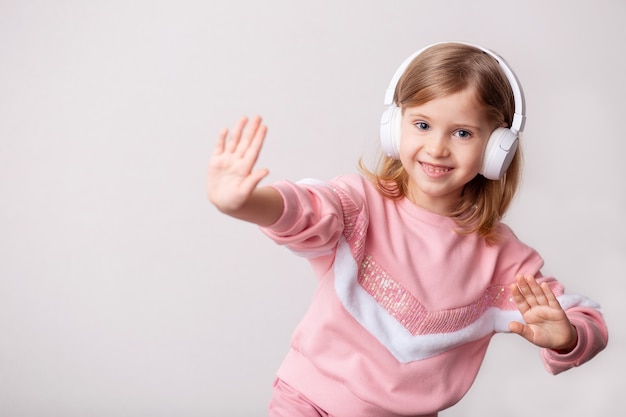 小さなブロンドの女の子がヘッドフォンで音楽を聴く