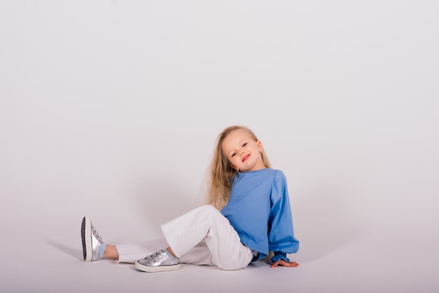 Little blonde girl posing sitting on the floor