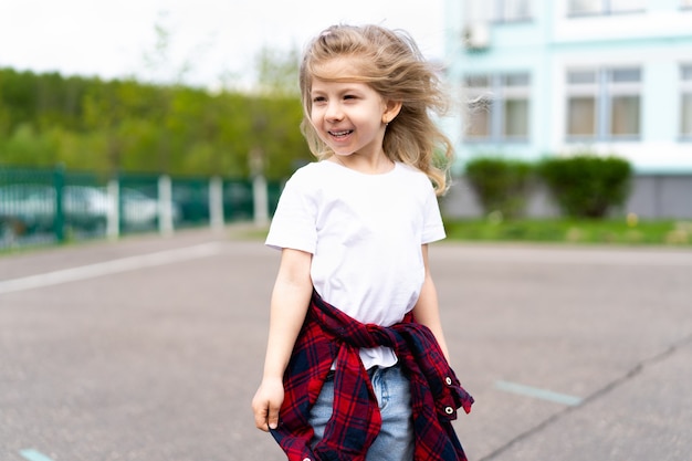 街のスケートボードに乗っている小さなブロンドの女の子。