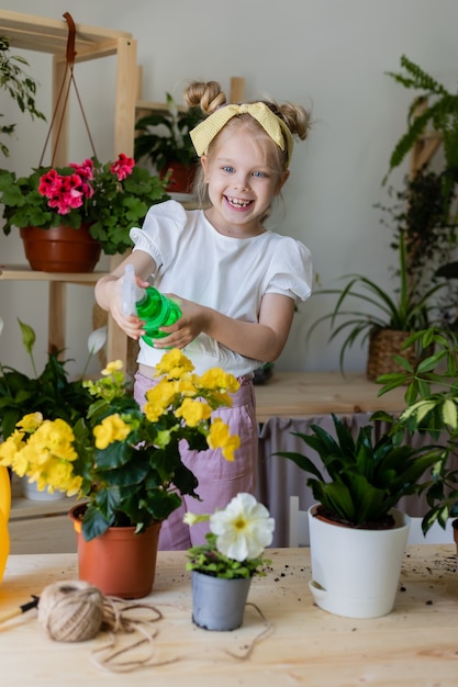 little blonde girl sprays from a bullet dispenser or waters indoor flowers Home gardening