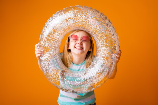 Little blonde girl in sunglasses holds a swimming circle in her hands