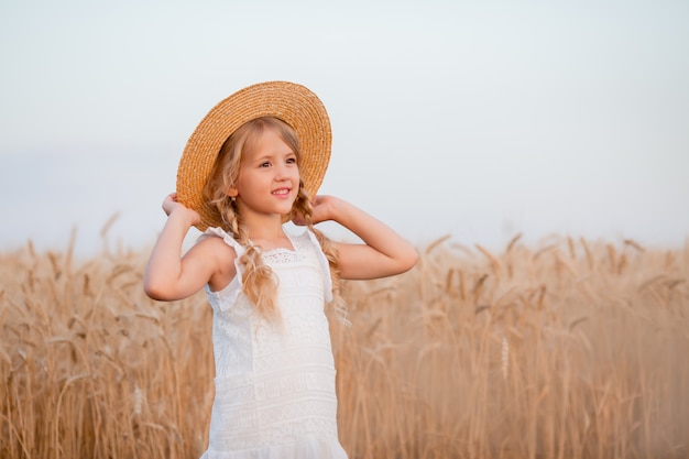 Little blonde girl walks in a summer wheat field