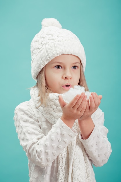 Piccola ragazza bionda in un cappello bianco e sciarpa